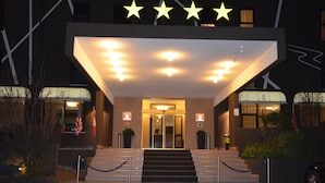 A hotel entrance with a star-shaped sign above the door, a set of stairs leading up to the entrance, and a security rope barrier in front. - Hotel Victoria (Vicenza)