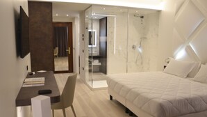 A modern bedroom with a bed, a desk, and a glass-enclosed shower area. - Hotel Victoria (Vicenza)