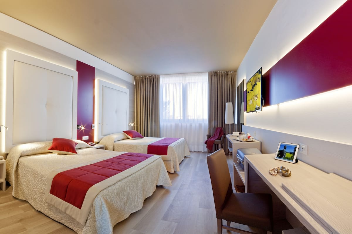 A hotel room with two beds, a desk, and a chair.