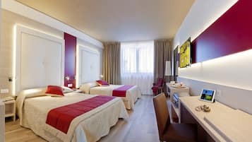 A hotel room with two beds, a desk, and a chair.