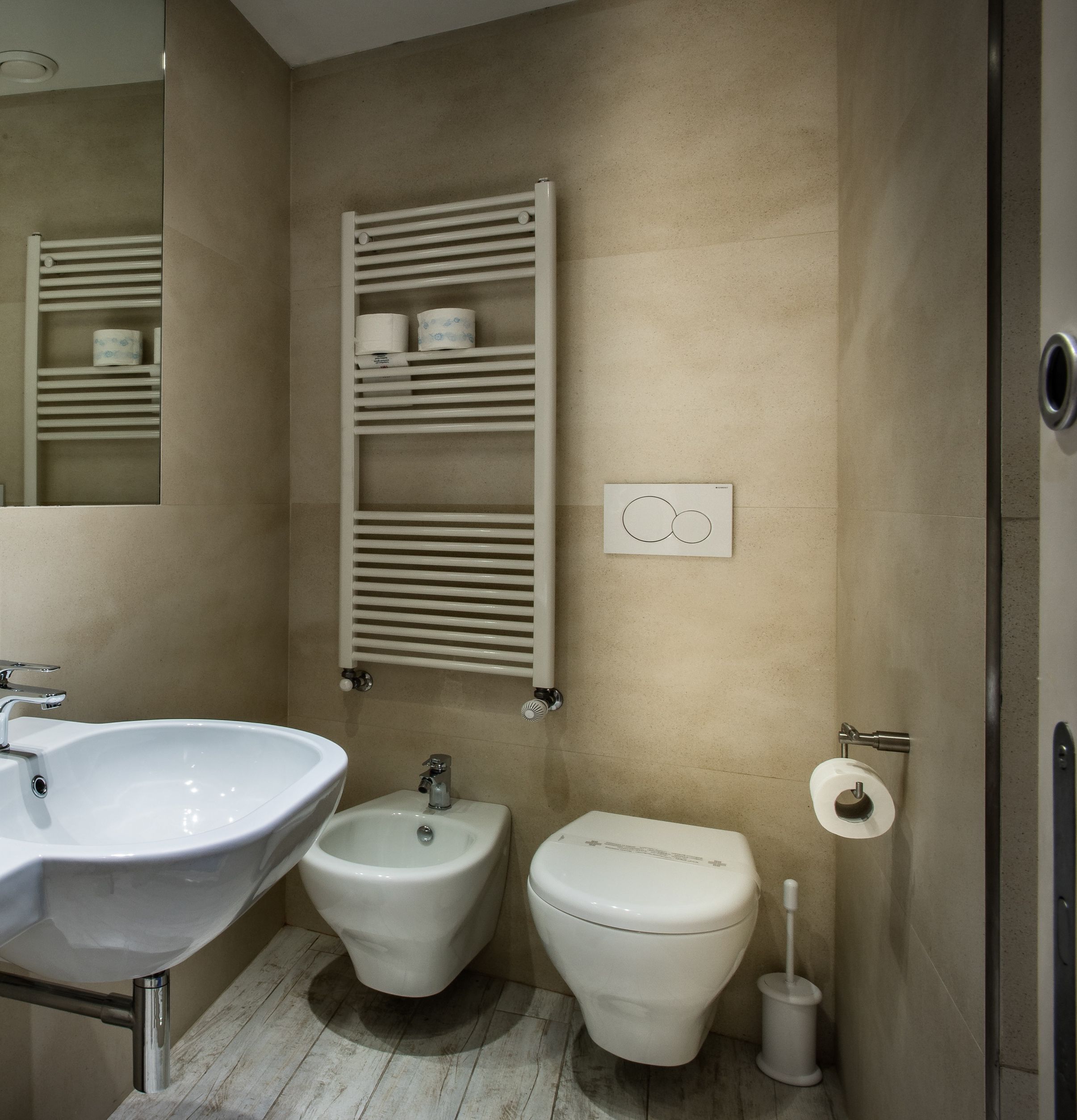 A bathroom with a white sink, a bidet, a toilet, and a towel rack.