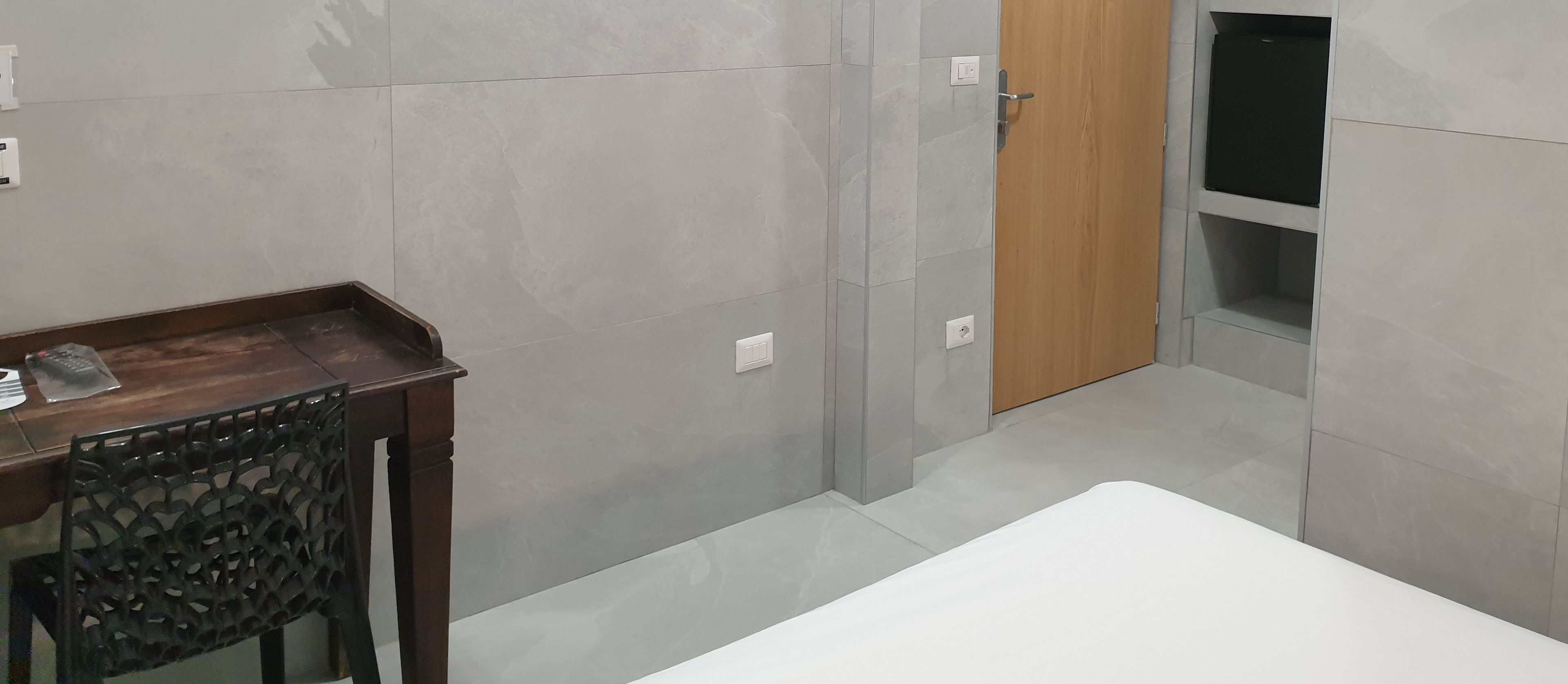 A bathroom with a wooden chair, a white sink, and a door leading to a shower area.