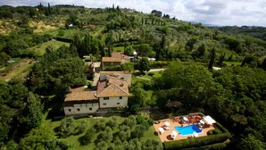 Una villa espaciosa con piscina, rodeada de exuberante vegetación y colinas.