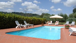 Piscina con sillones de descanso y zona de bar, con una botella de champán y copas.