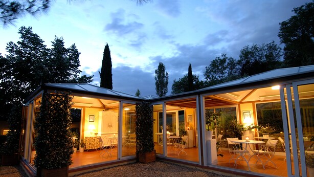 Una casa moderna con paredes de vidrio y un patio.