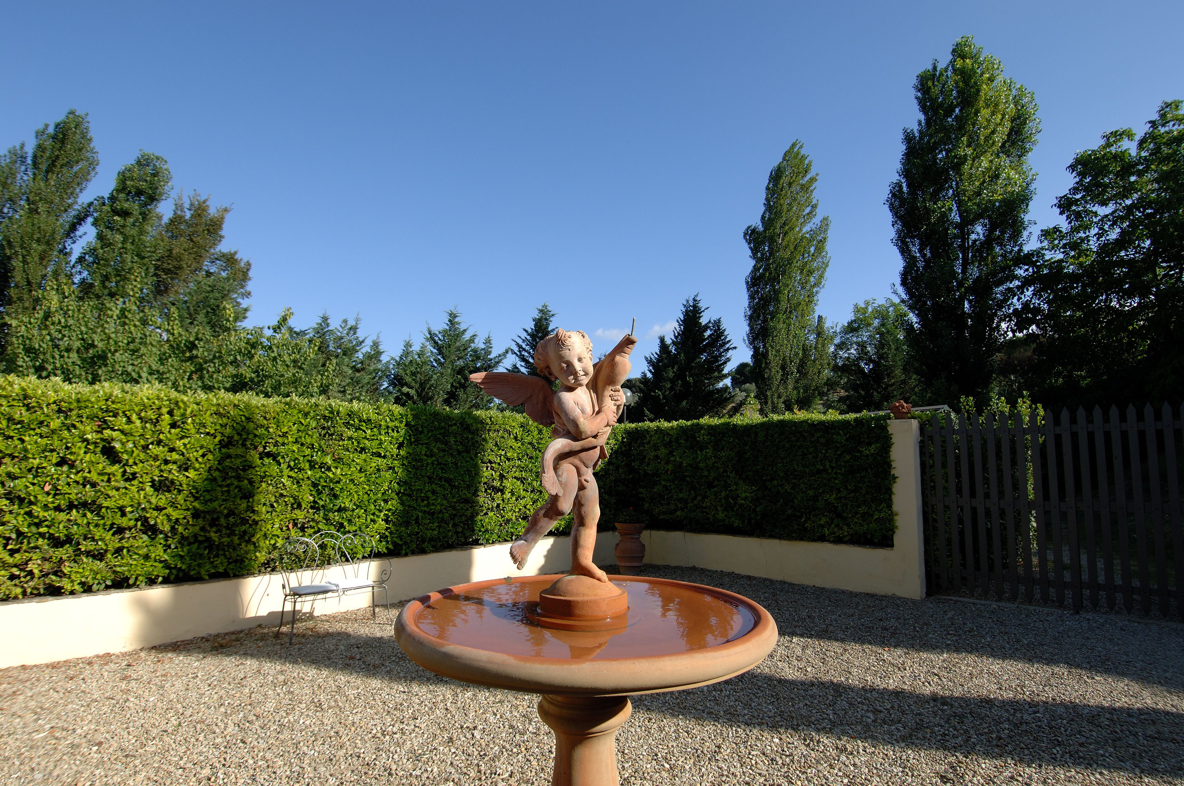 A garden with a statue of a figure on a pedestal, surrounded by well-maintained hedges and trees.