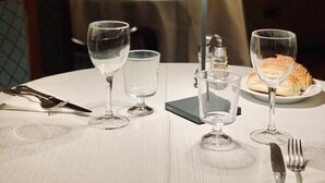 A dining table set with wine glasses, a plate of food, and cutlery. - Massimo Plaza Hotel (Palermo)