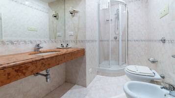 Un bagno con lavabo in marmo, doccia, WC e bidet.