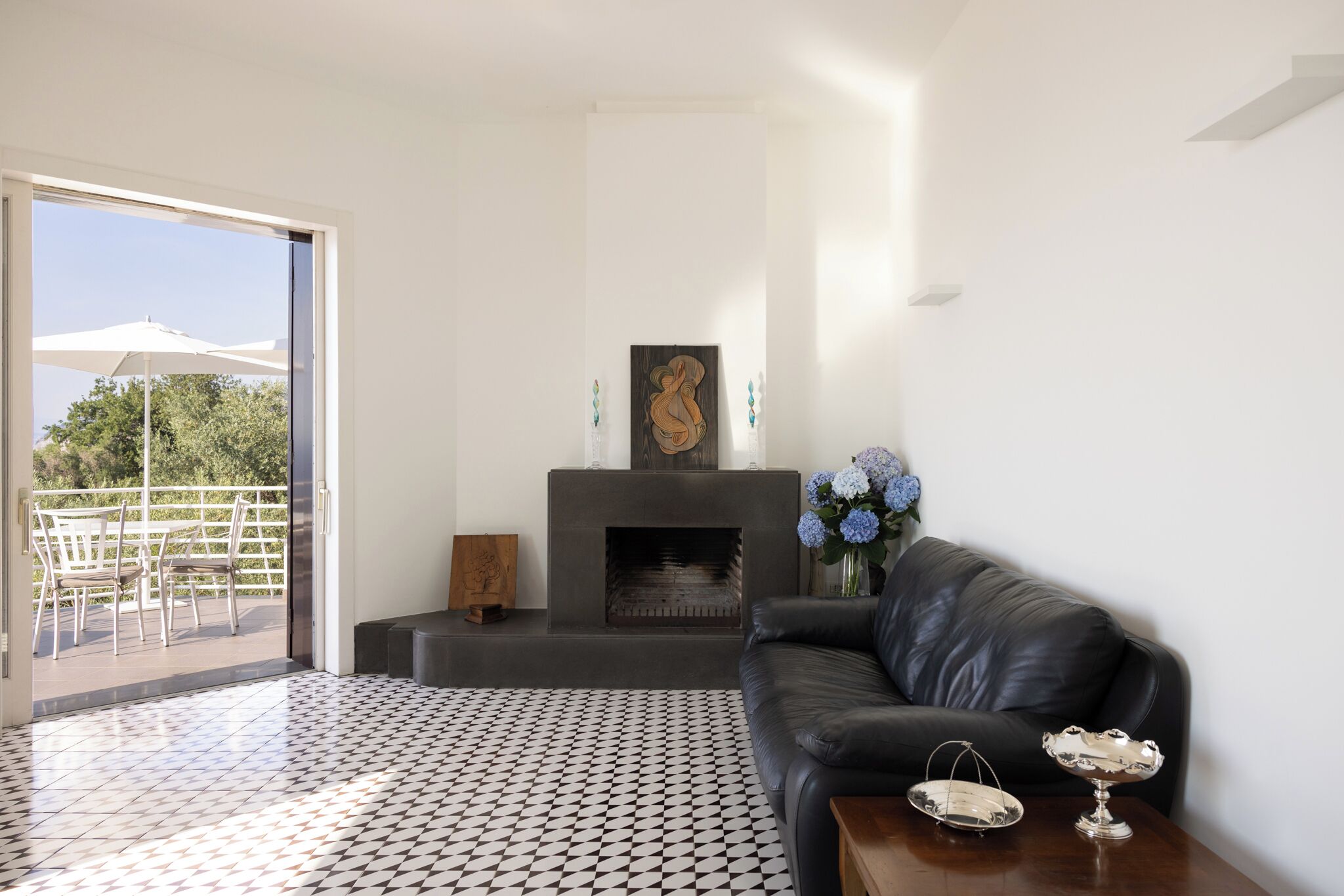 Ein modernes Wohnzimmer mit Kamin, einer schwarzen Ledersofa und einem gemusterten Boden.