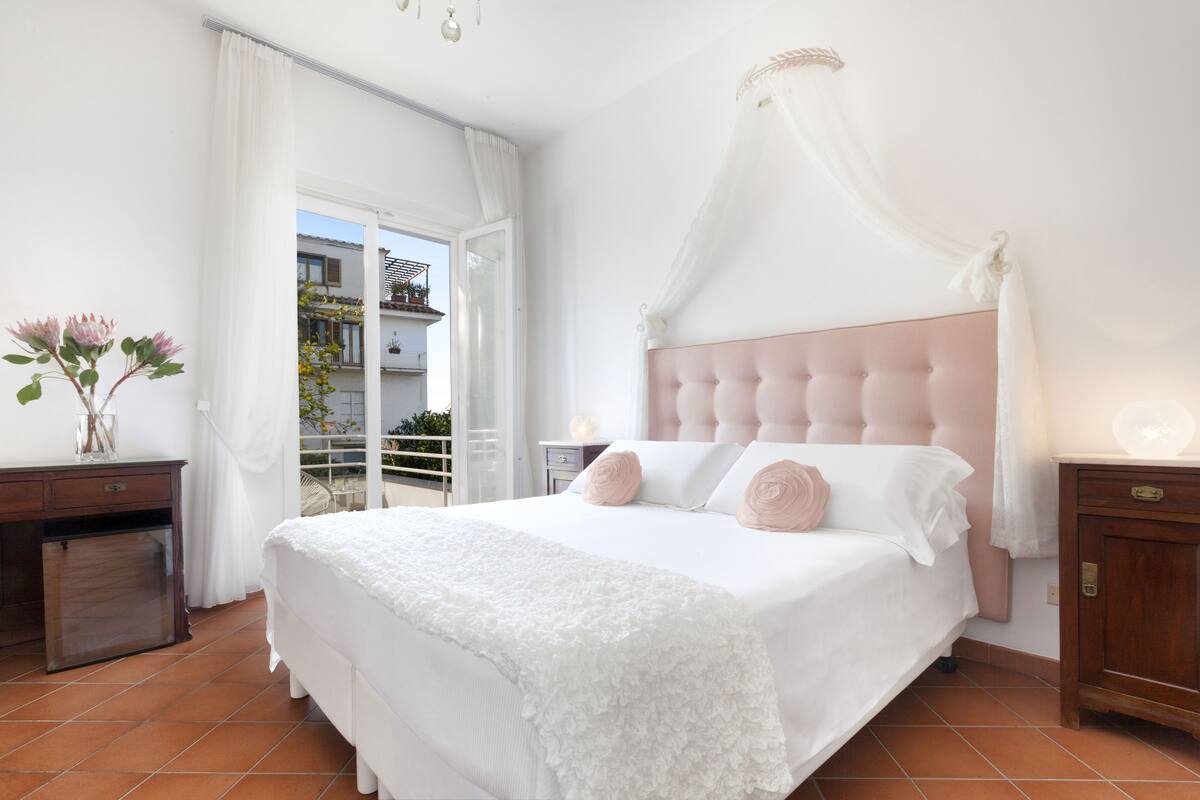 Een slaapkamer met een groot bed, een nachtkastje, een kast en uitzicht op het balkon.