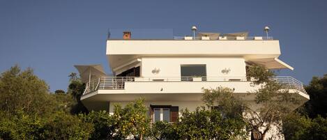 A multi-story building with balconies, a garage, and a flat roof with solar panels.