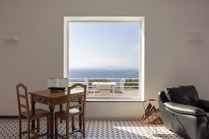 A room with a large window, a dining table with chairs, a leather sofa, and a patterned floor. - Villa Oriana Relais (Sorrento)