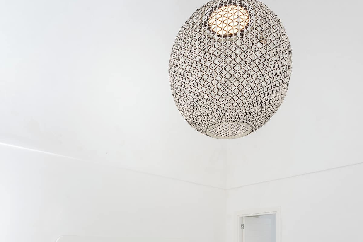 A minimalist bedroom with a bed, bedside tables, and a hanging light fixture.