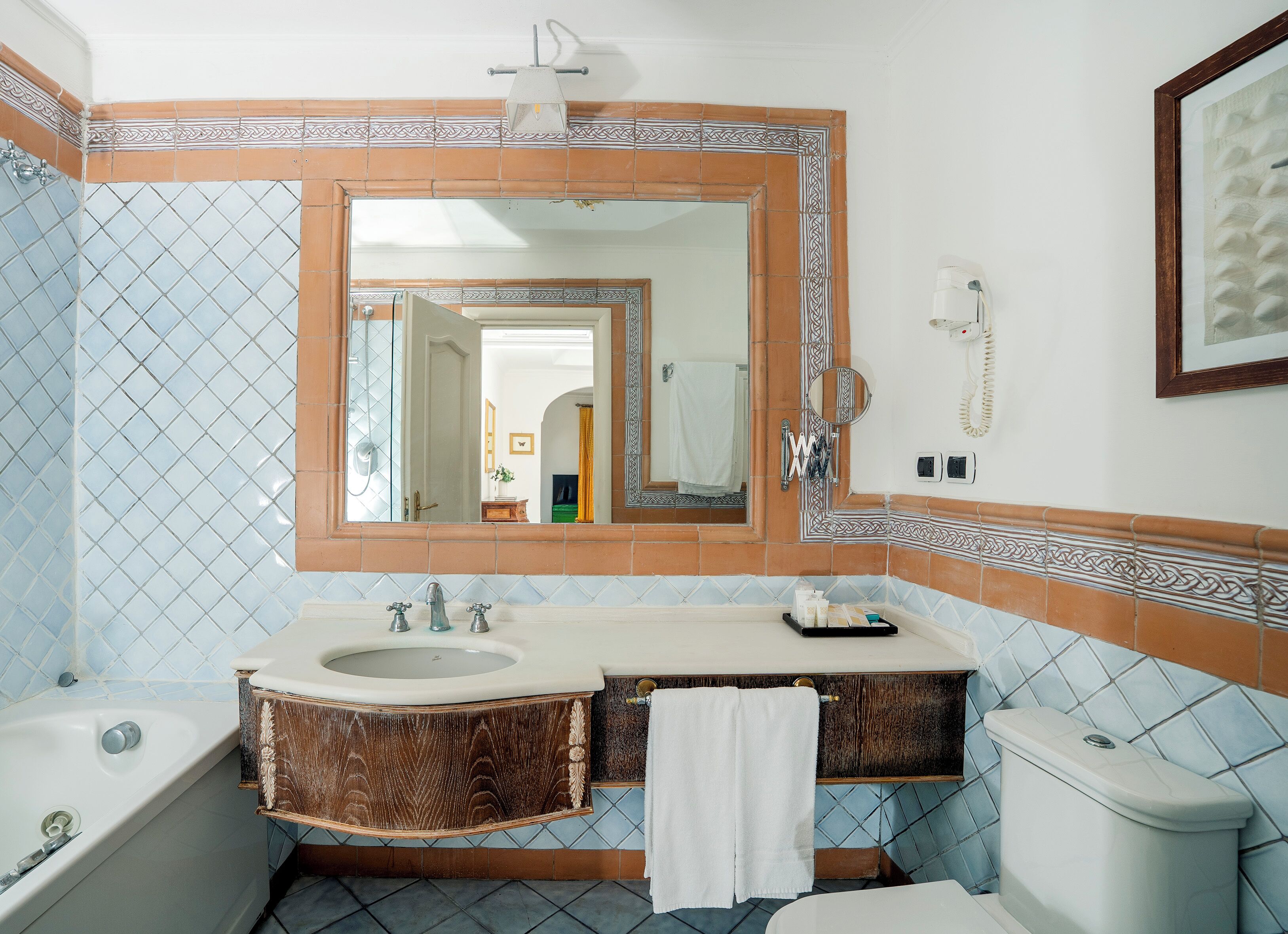 A bathroom with a large mirror, a sink, a toilet, and a bathtub.