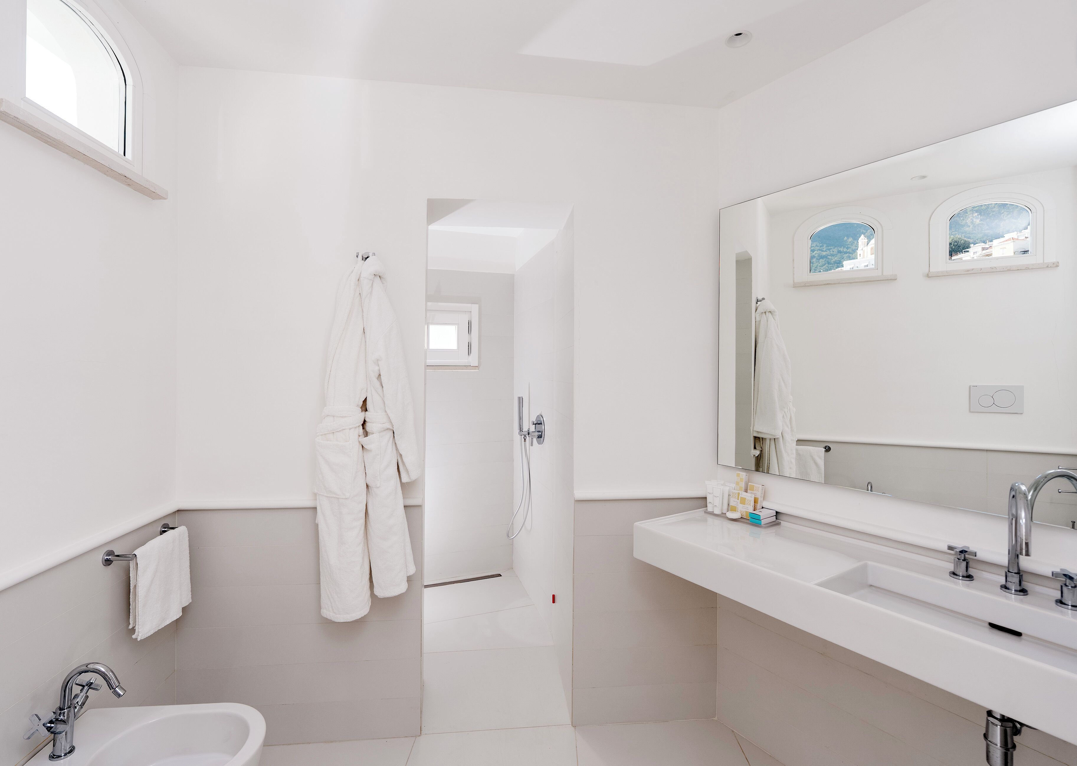 A modern bathroom with a large mirror, a bathtub, a sink, and a shower.