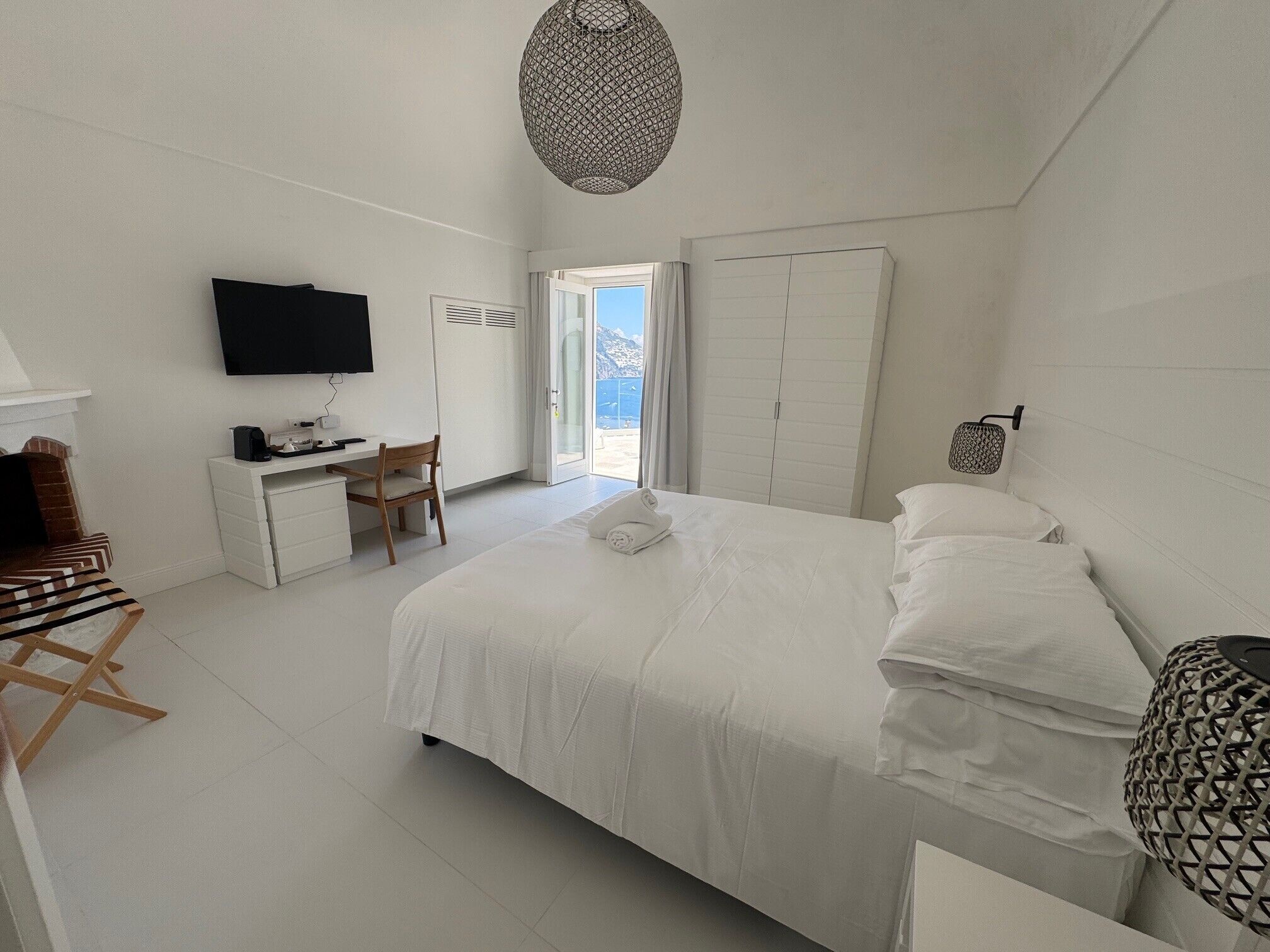 A bedroom with a bed, a desk, a chair, a television, and a wardrobe.