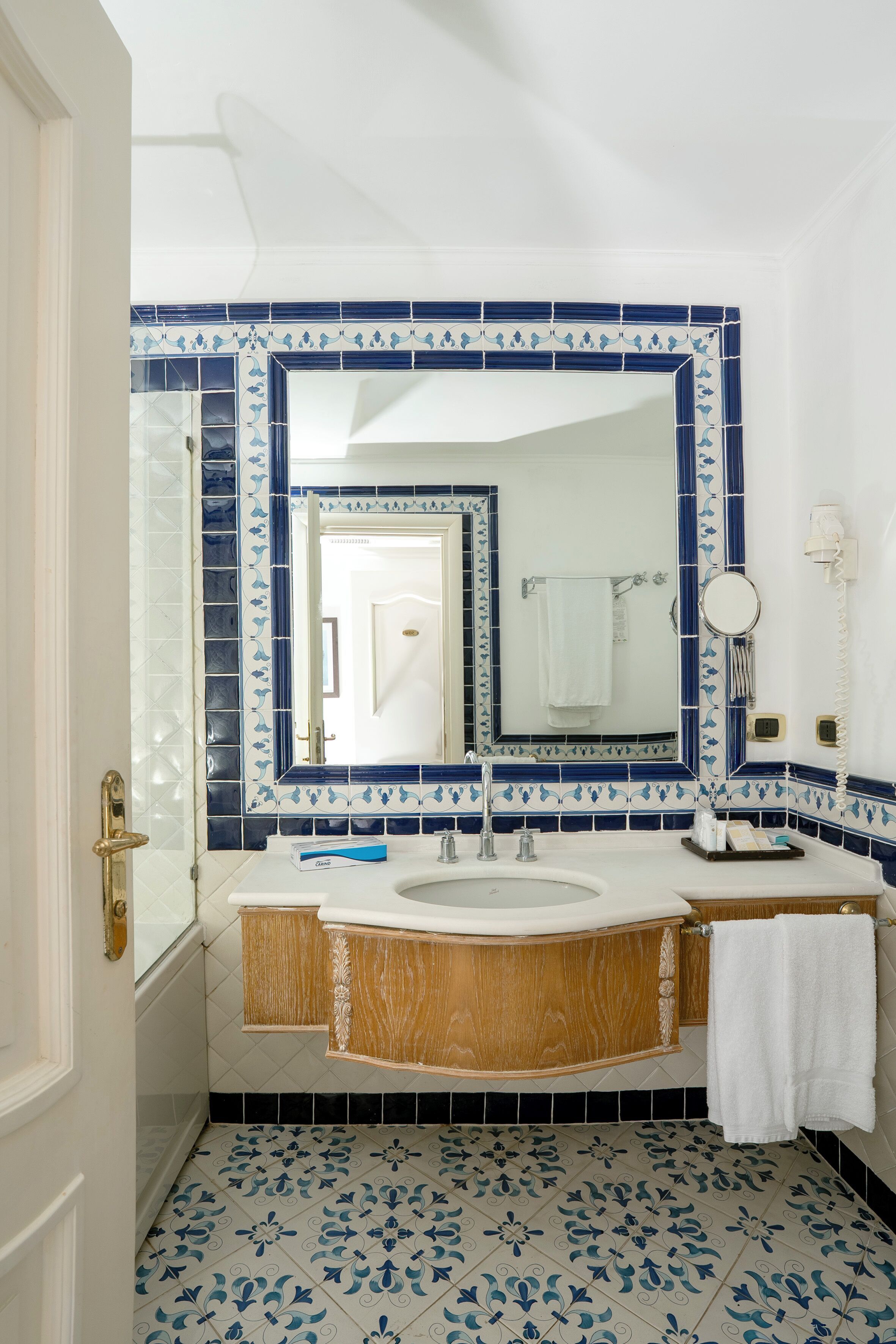 A bathroom with a white sink, a mirror, and a towel hanging on the wall.