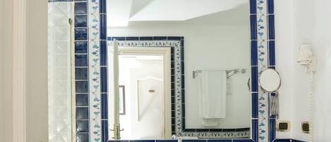 A bathroom with a white sink, a mirror, and a towel hanging on the wall.