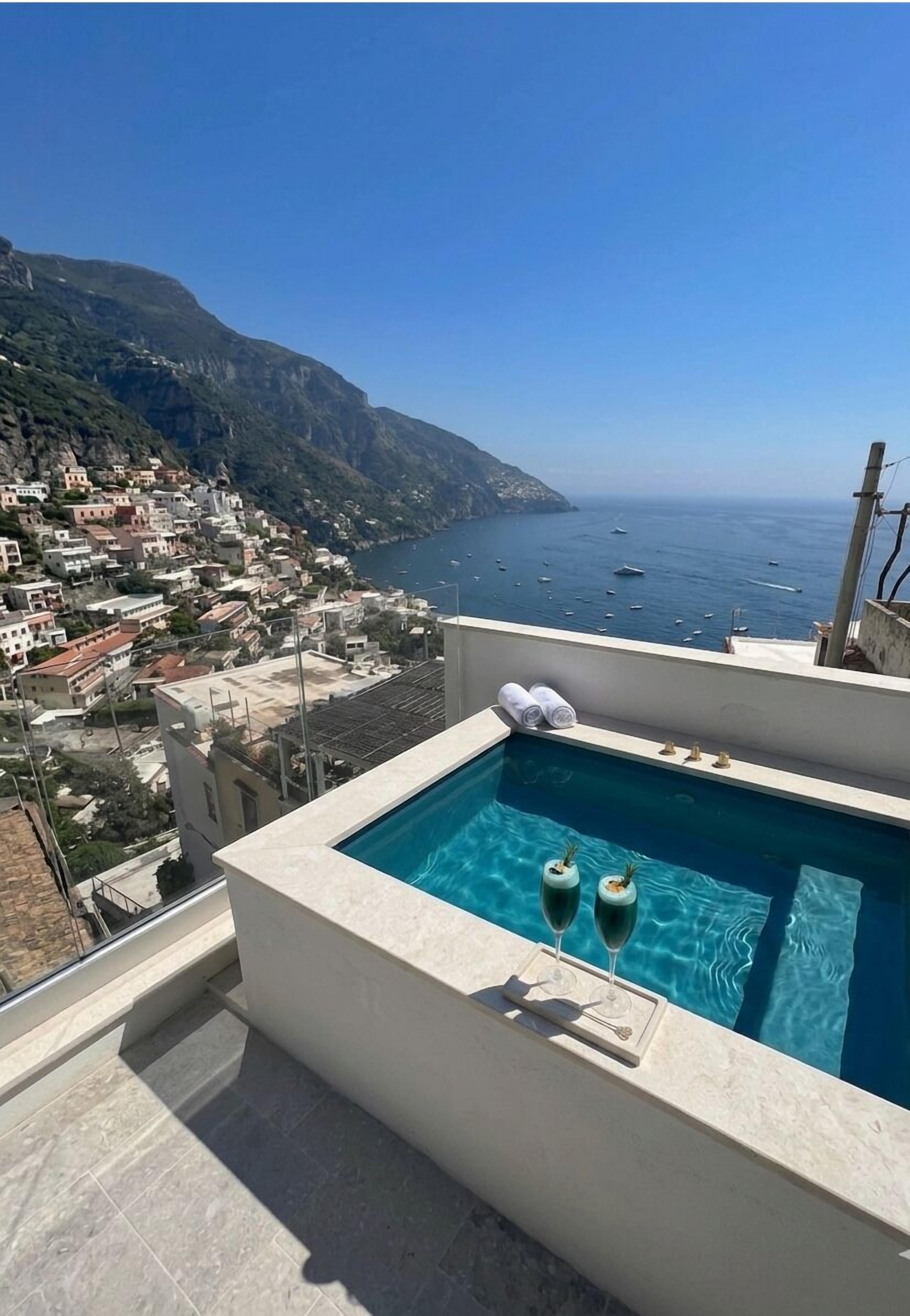 Una piscina en la azotea con vistas despejadas al mar y a un pueblo costero.