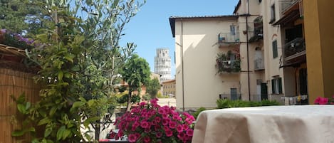 A street view with a building featuring balconies and a tower in the background.