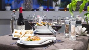 Une table à manger dressée avec des assiettes remplies de nourriture, des verres à vin et des salières et poivrières.