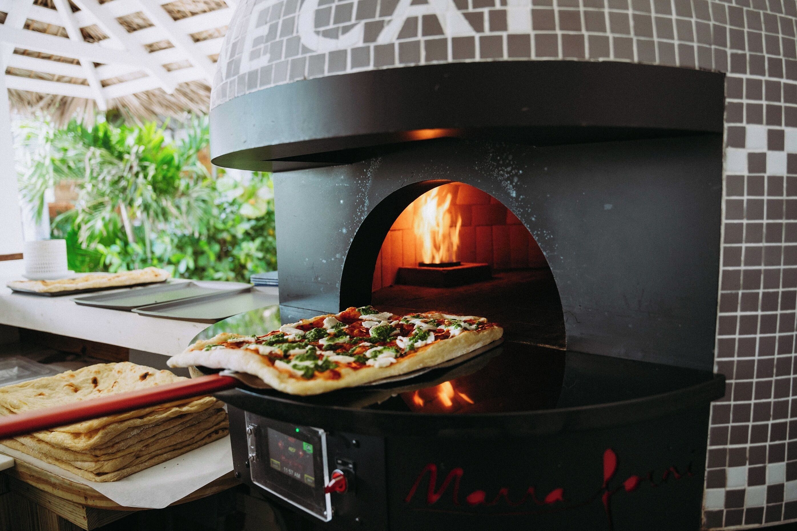 A brick oven pizza oven with a pizza being cooked inside.
