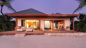 A modern beachfront house with a spacious living area, a visible kitchen, and a large glass door leading to the interior. - Pine Cay, Turks and Caicos (Pine Cay)