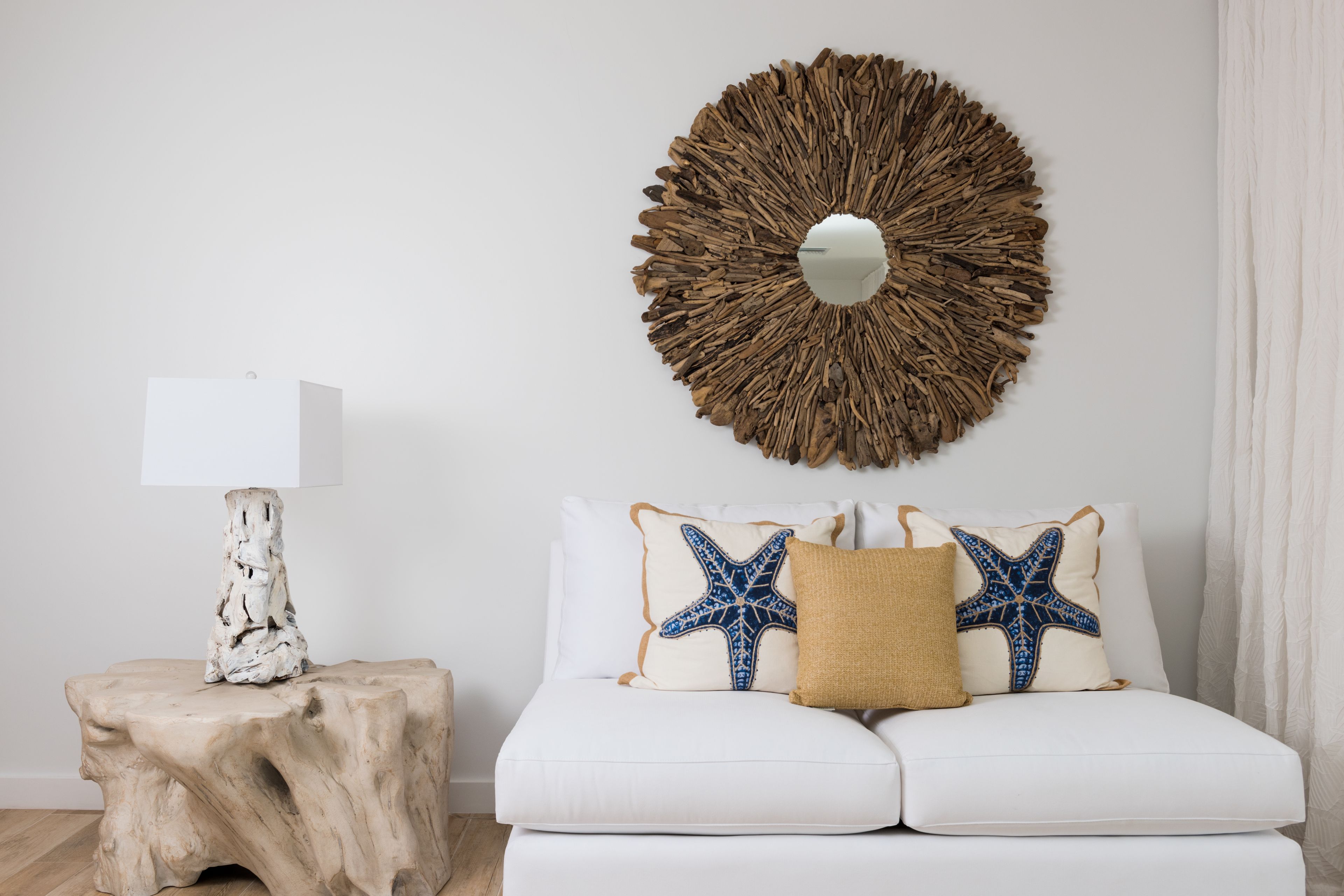 Un divano bianco con cuscini a forma di stella marina, un tavolino in legno e un'ampia decorazione circolare a parete.