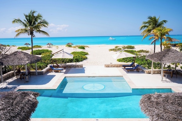 Una piscina al aire libre, sombrillas, sillones reclinables de piscina
