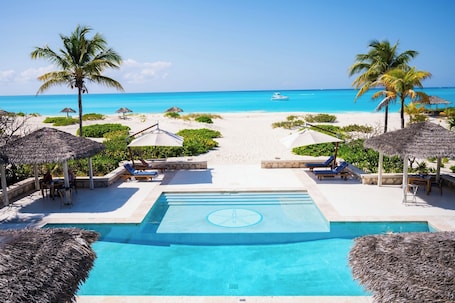 Una piscina al aire libre, sombrillas, sillones reclinables de piscina