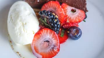 Um prato de sobremesa com bolo de chocolate, uma bola de sorvete de baunilha e frutas vermelhas frescas.