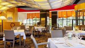 Un restaurante con mesas redondas, sillas y un techo de diseño único.