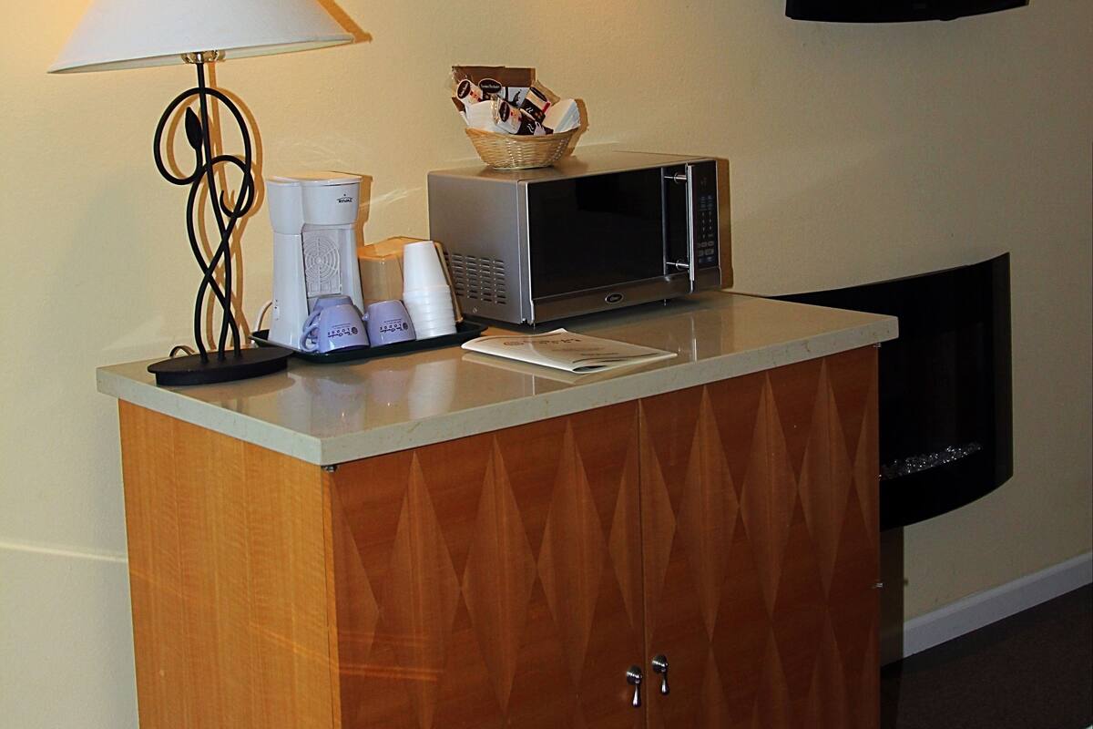 Une chambre d’hôtel équipée d’un meuble en bois, d’un four à micro-ondes, d’une lampe et d’un téléviseur à écran plat fixé au mur.