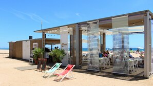 A beachside restaurant with outdoor seating, a wooden structure, and a view of the beach. - htop Royal Sun (Santa Susanna)