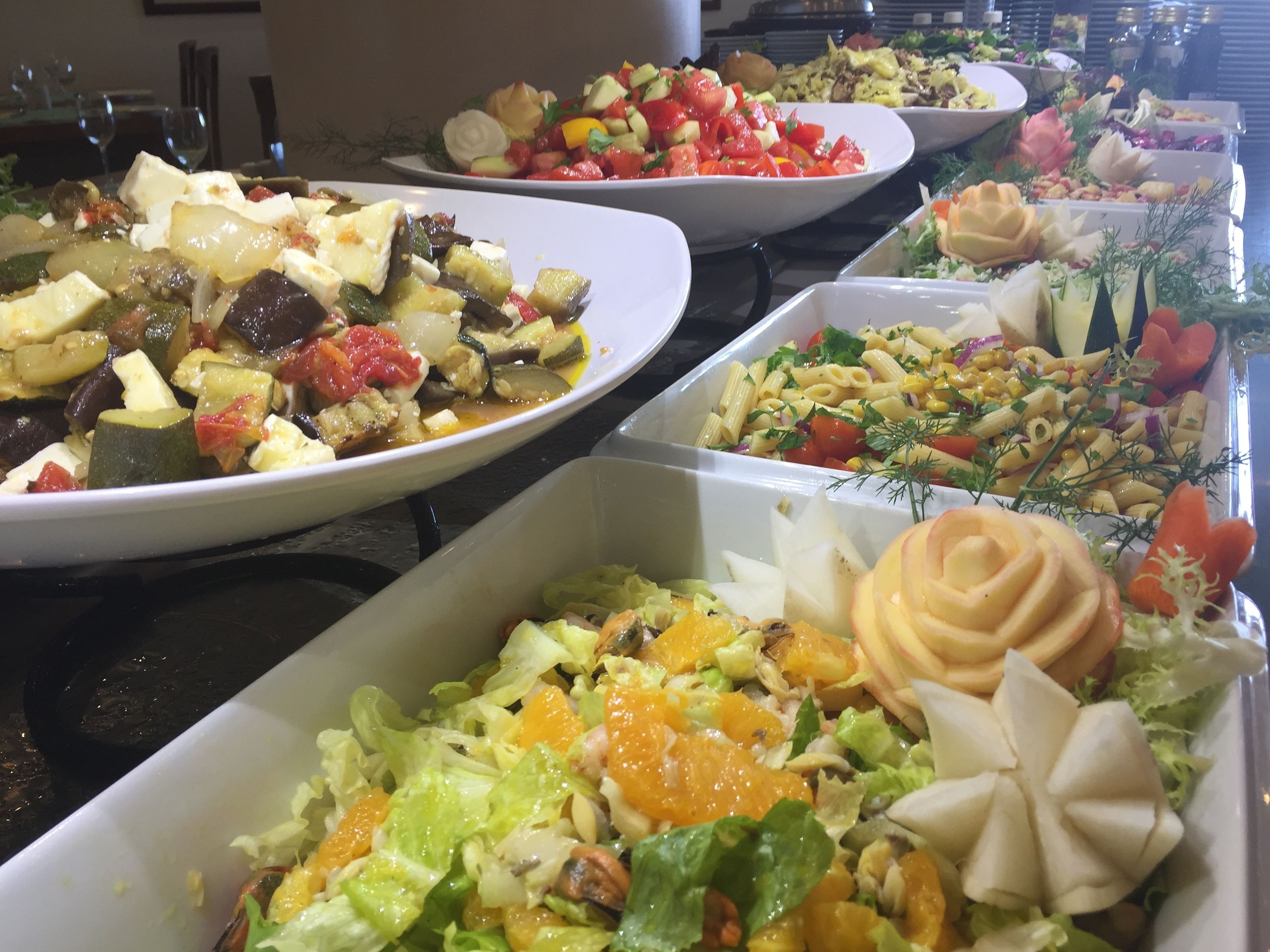 A buffet with various dishes including salads, pasta, and vegetables.