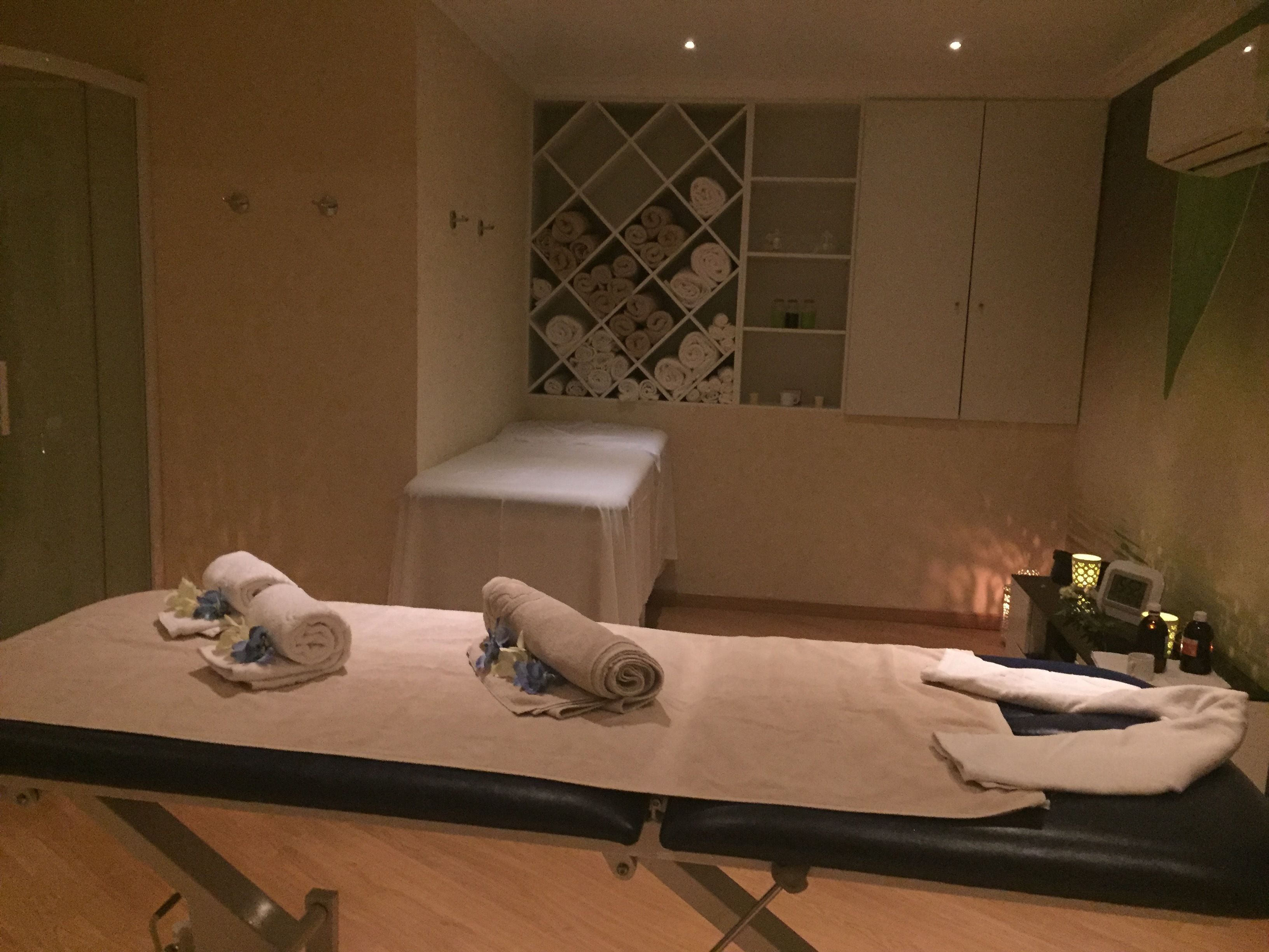 Ein Massagetisch mit Handtüchern und ein kleiner weißer Tisch daneben.