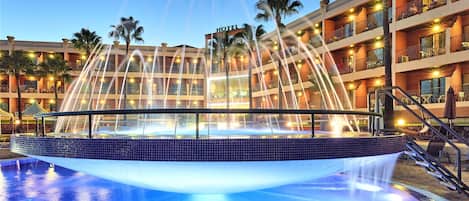 Alberca techada, alberca al aire libre y sombrillas en la alberca