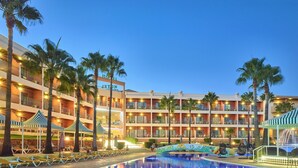 A hotel with multiple balconies, a swimming pool, and palm trees. - Hotel Baia Grande (Albufeira)