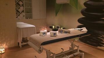 Ett rum för massagebehandlingar med en massagebänk, handdukar och en liten lampa.