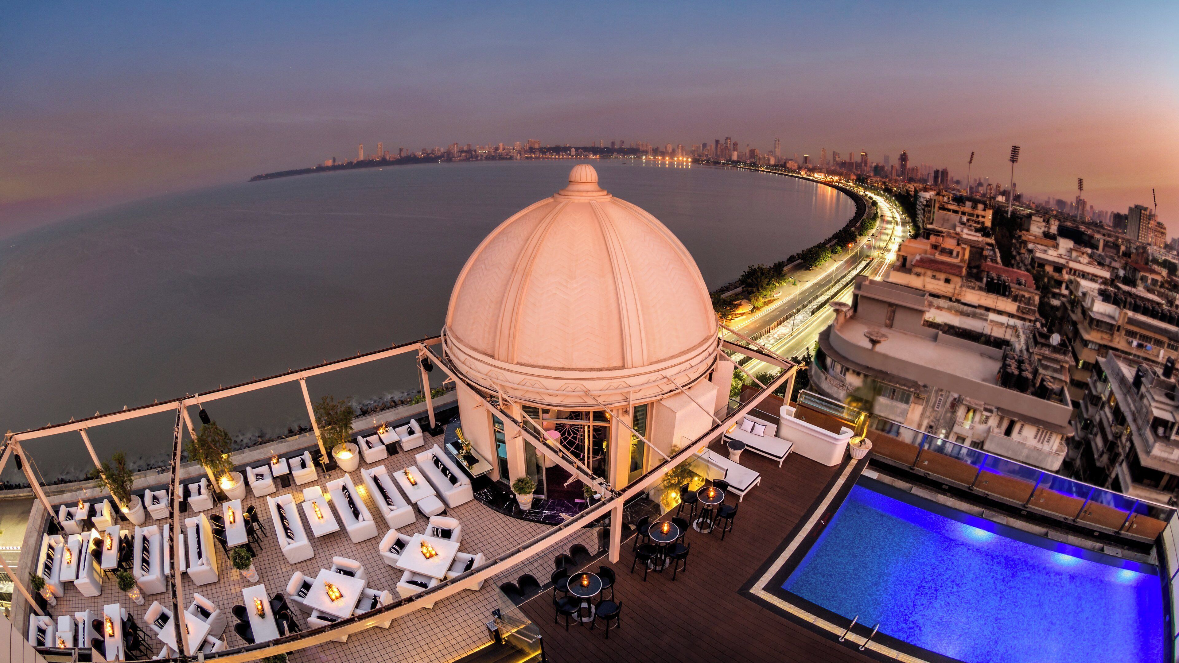 Une terrasse sur le toit dotée d’une piscine, d’un espace salon et offrant une vue sur le panorama urbain.