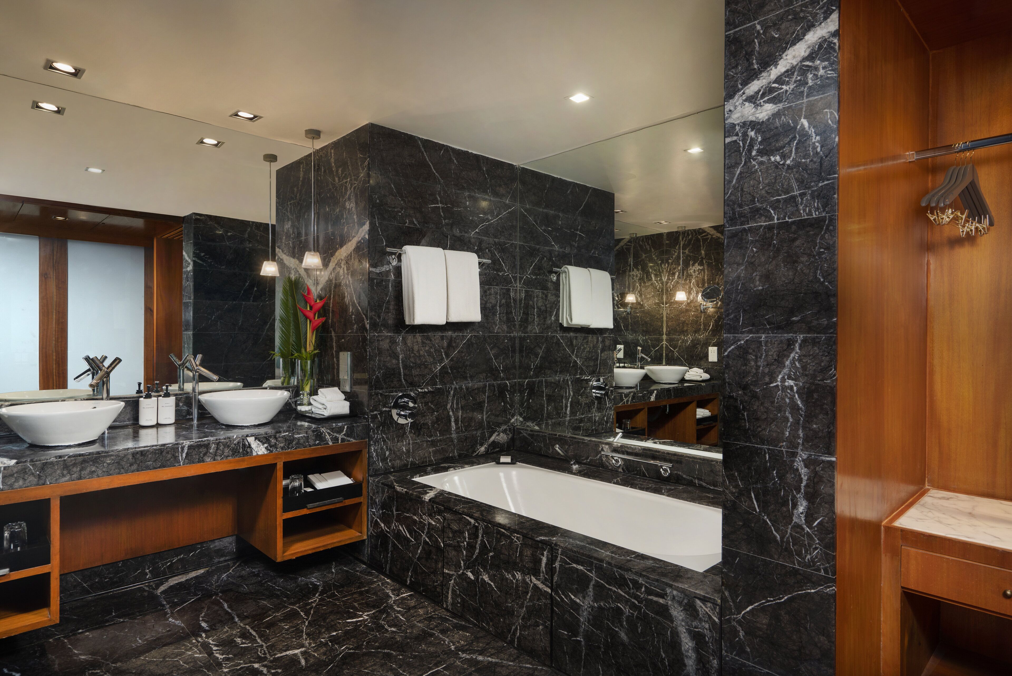 Un baño moderno con una bañera grande, dos lavabos y un tocador con espejo.