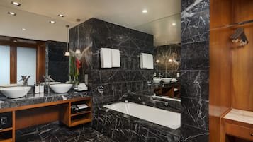 Un baño moderno con una bañera grande, dos lavabos y un tocador con espejo.