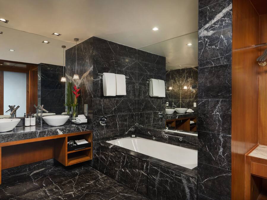 Un baño moderno con una bañera grande, dos lavabos y un tocador con espejo.