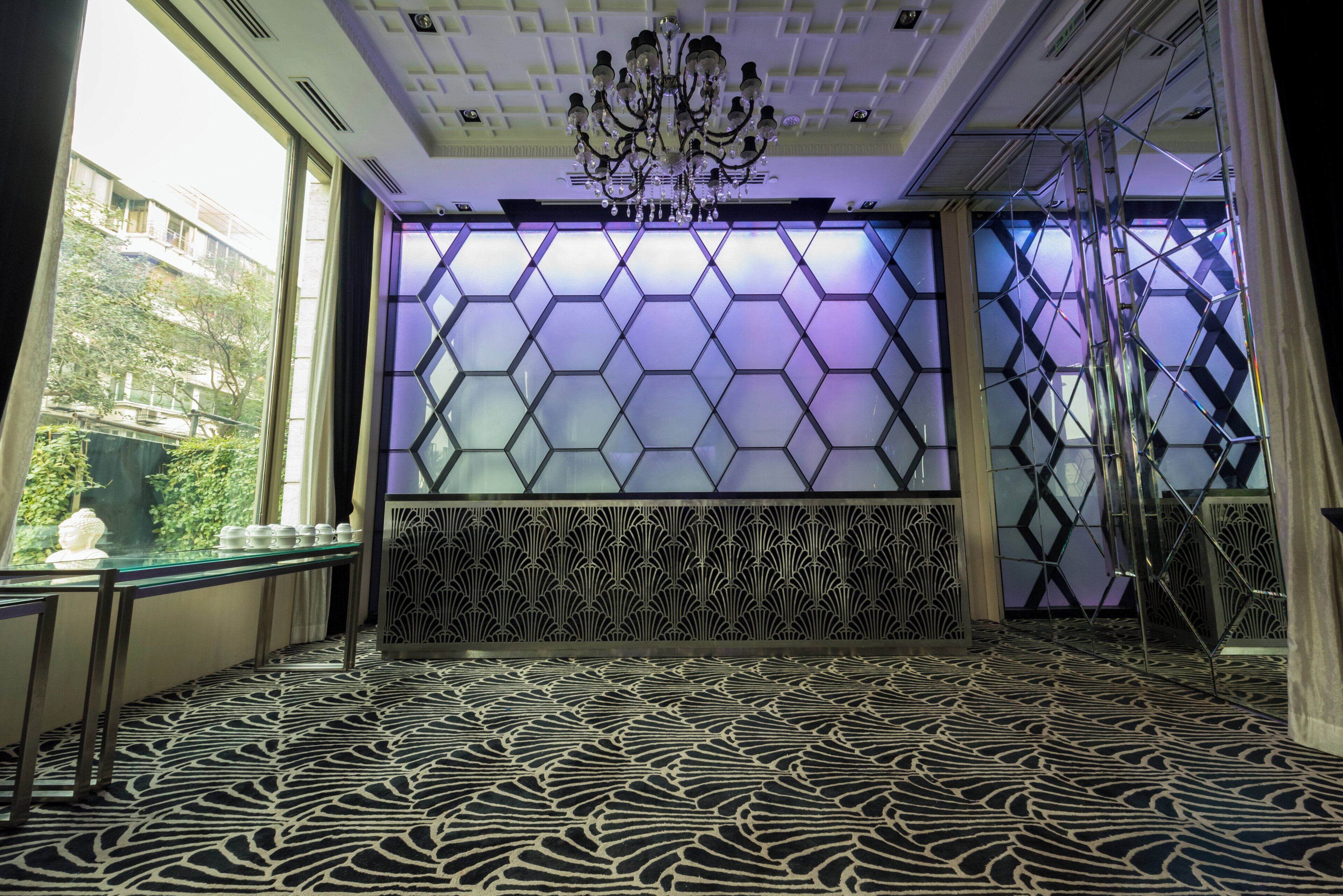 Una habitación con piso estampado, pared decorativa con patrones geométricos y un candelabro.