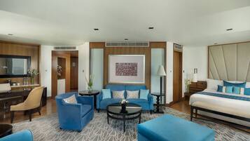 Una habitación de hotel moderna con una cama grande, un sofá, una mesita de centro y un escritorio con una silla.