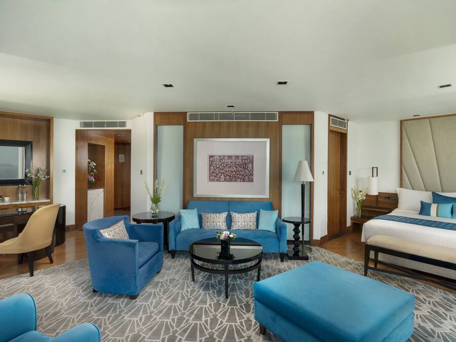 Una habitación de hotel moderna con una cama grande, un sofá, una mesita de centro y un escritorio con una silla.