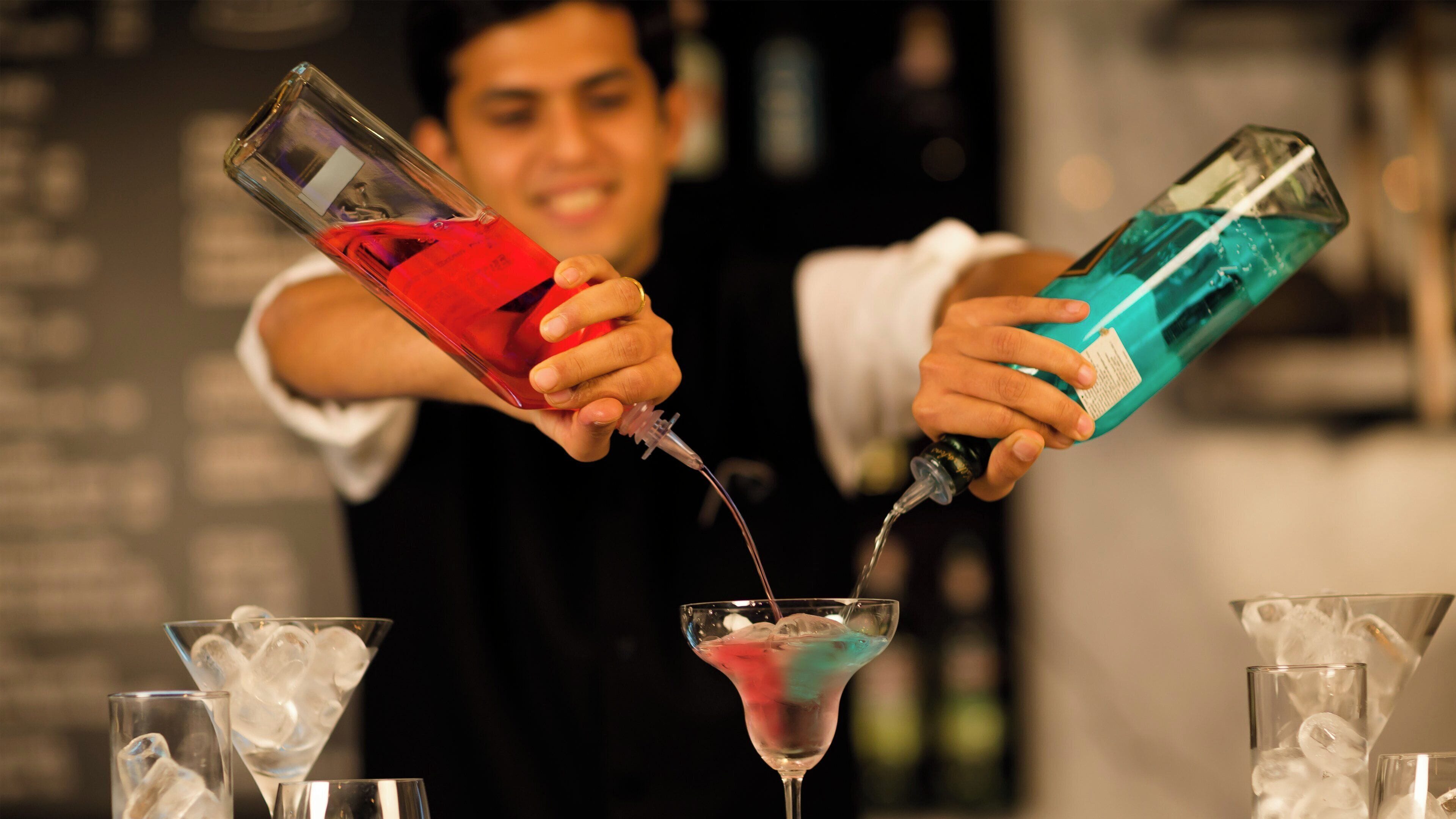A person pouring a drink into a martini glass.