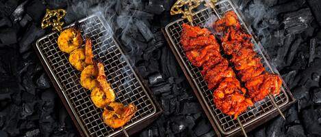 Two metal grills with food on them, placed on a bed of charcoal.