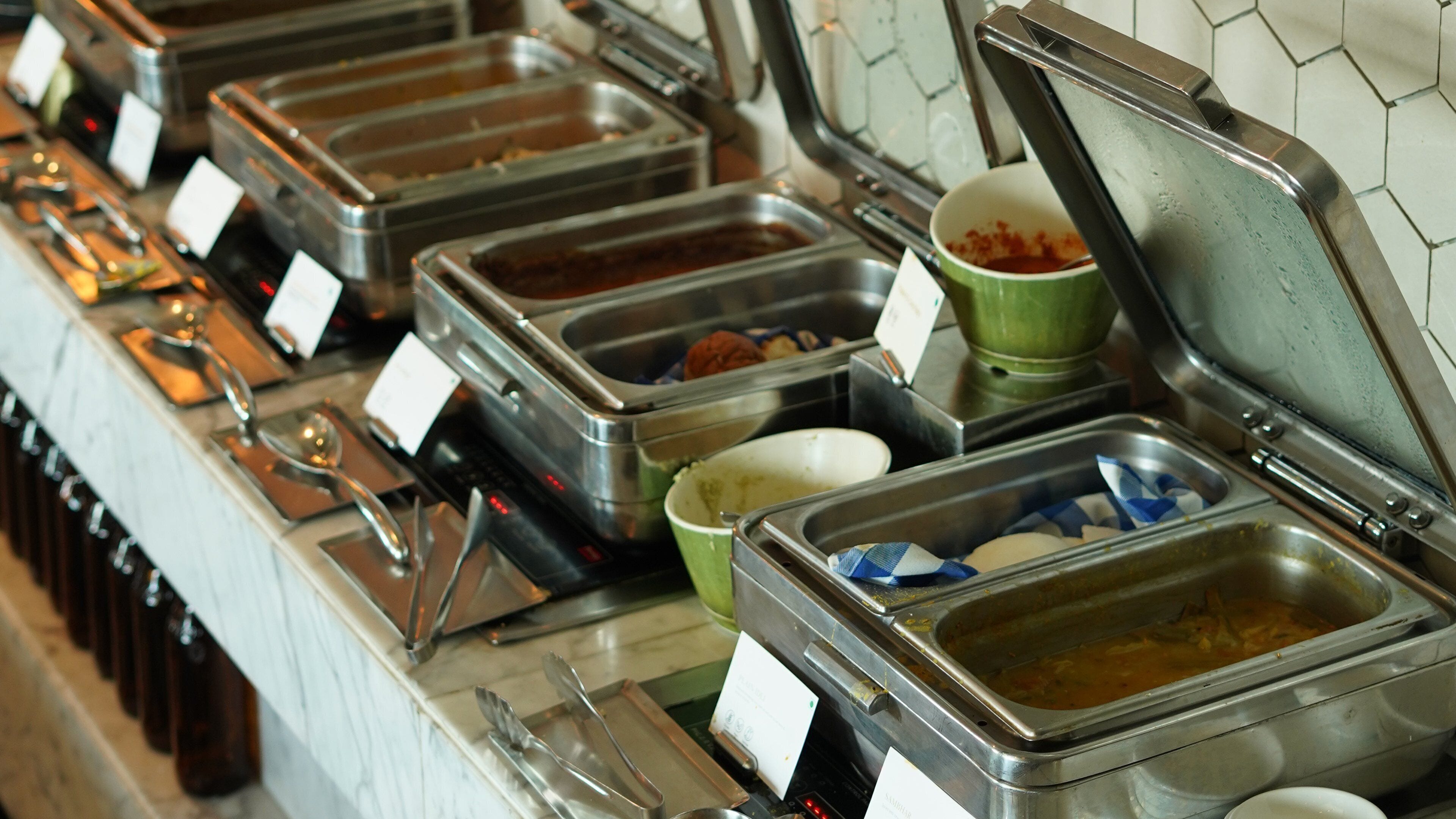 A buffet setup with multiple food containers and utensils.