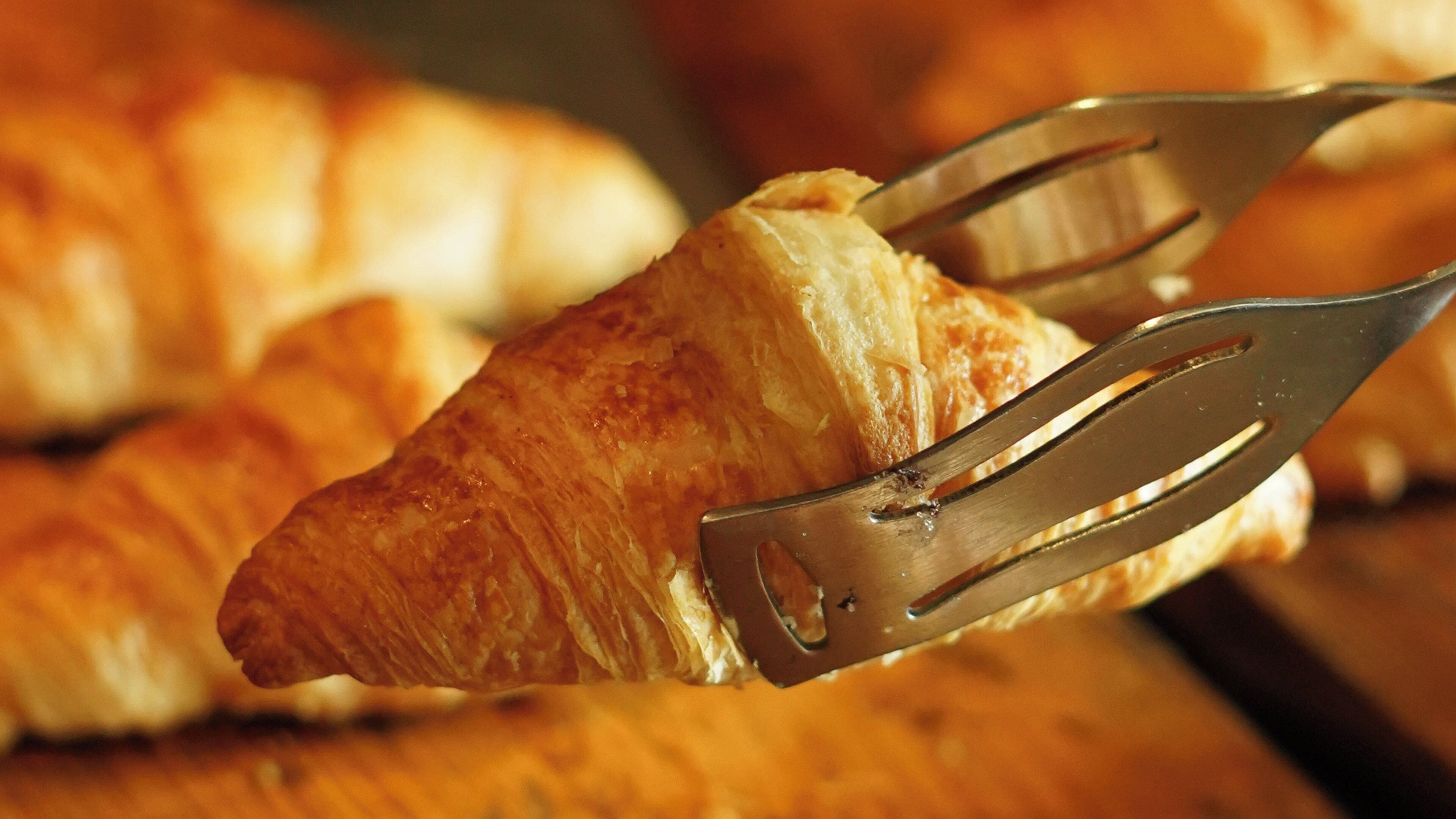 Un croissant sostenido por un tenedor.